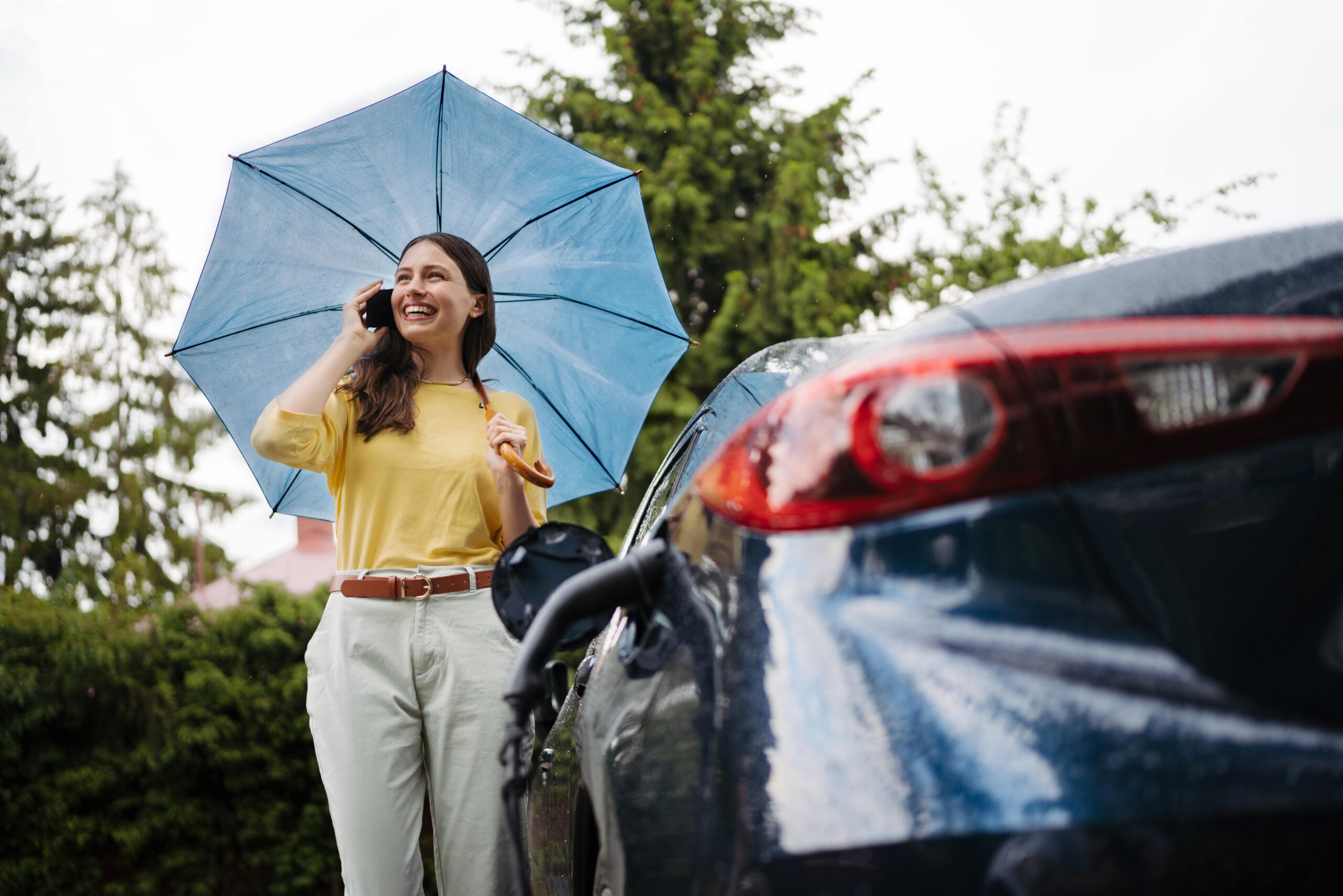 woman-calling-standing-under-umbrella-while-charg-2024-10-22-13-26-09-utc-min